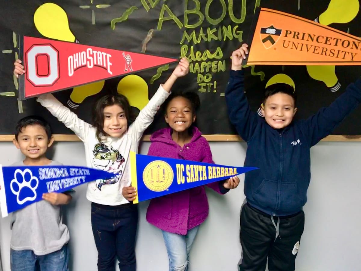 Four club members holding up college pennants