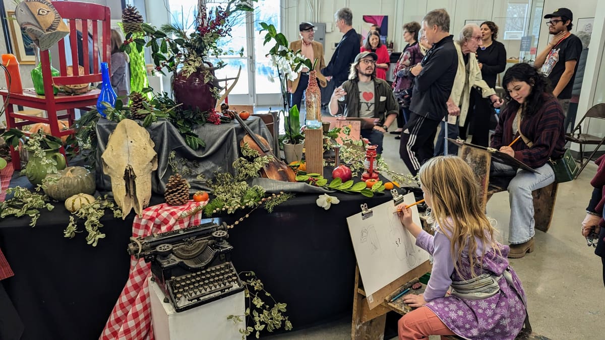 A girl sketching a still life at an easel during an open house