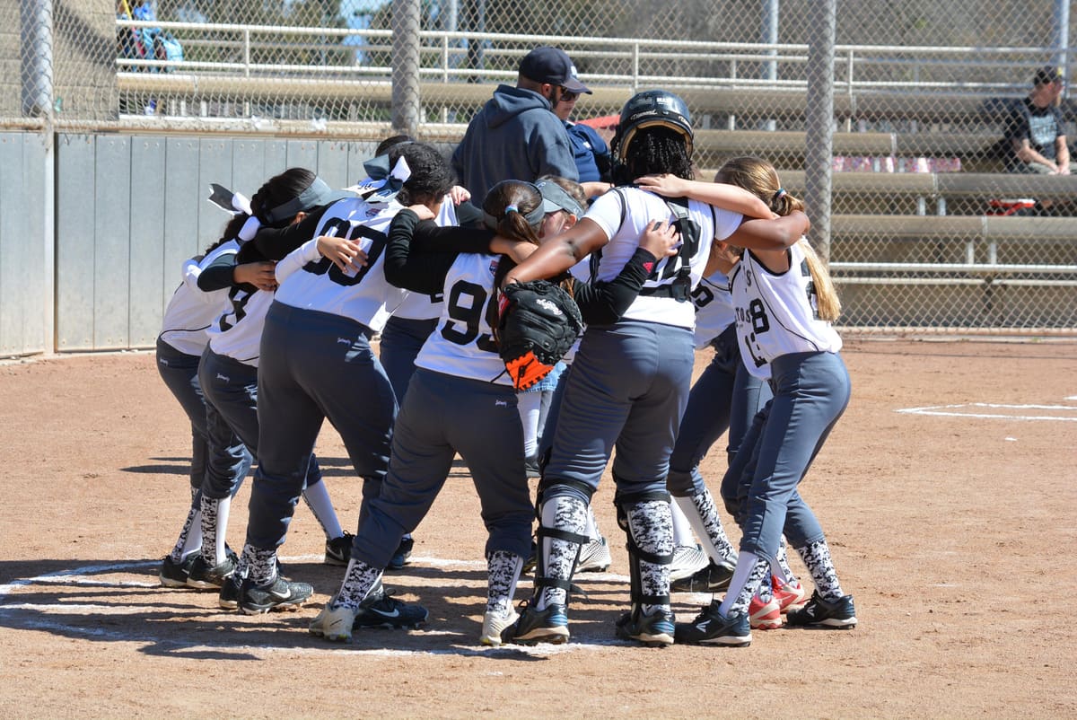 A girls' softball team huddles on the infield before a game