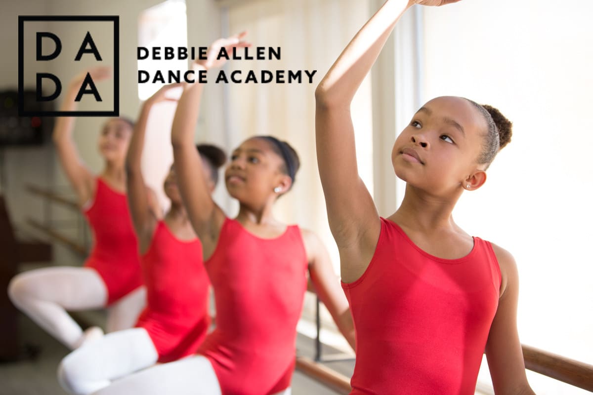 Young dancers in red leotards at the ballet barre