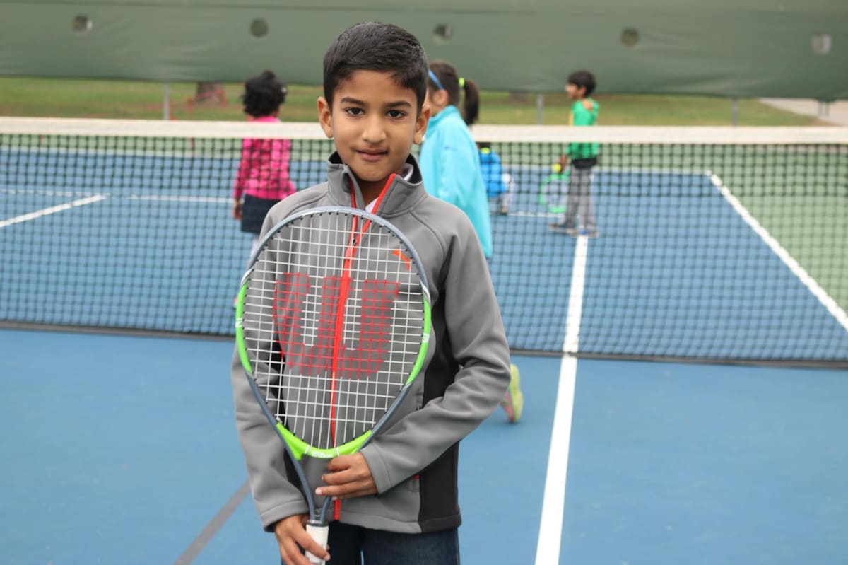 A boy holding a racket on a court at the Fremont Tennis Center