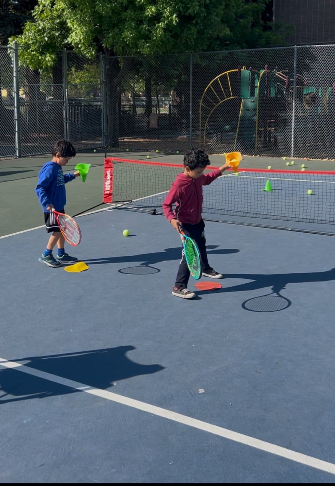 Two young kids playing mini tennis on a small red-ball court