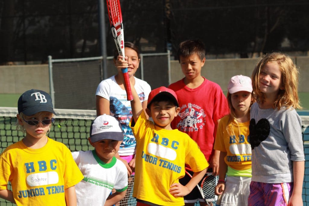 Young players in Harbor Bay Club junior tennis shirts at the net