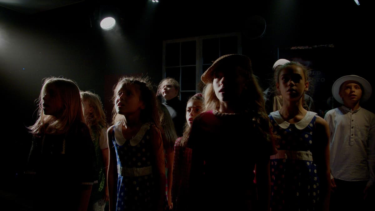 Children singing together on a dimly lit stage