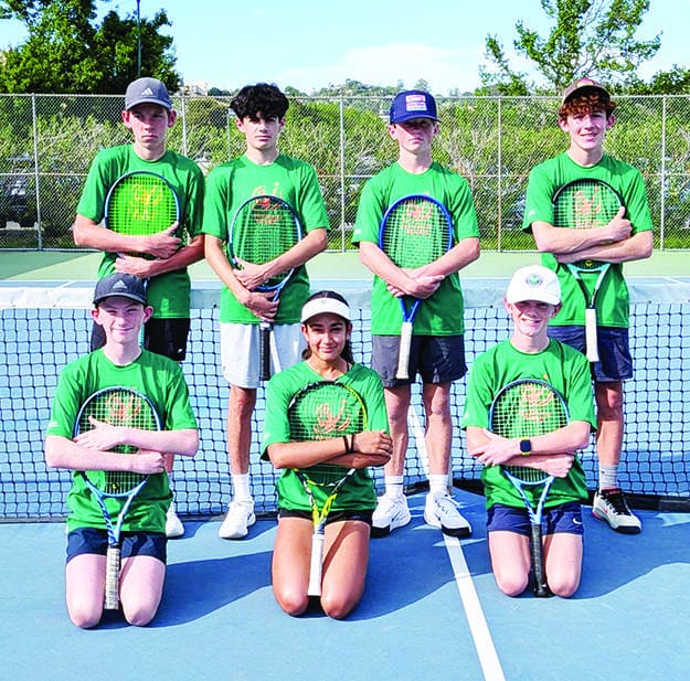Seven junior players with racquets on a tennis court