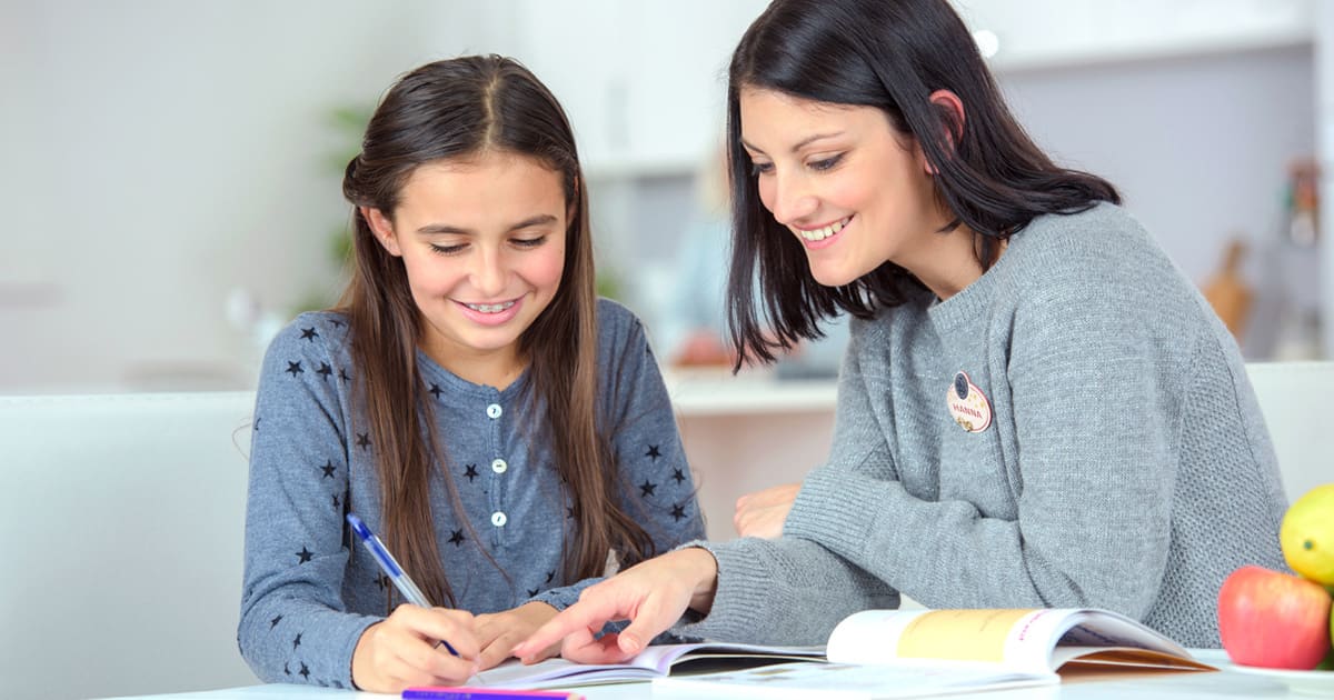 A clinician and a girl working through a reading book together at a table