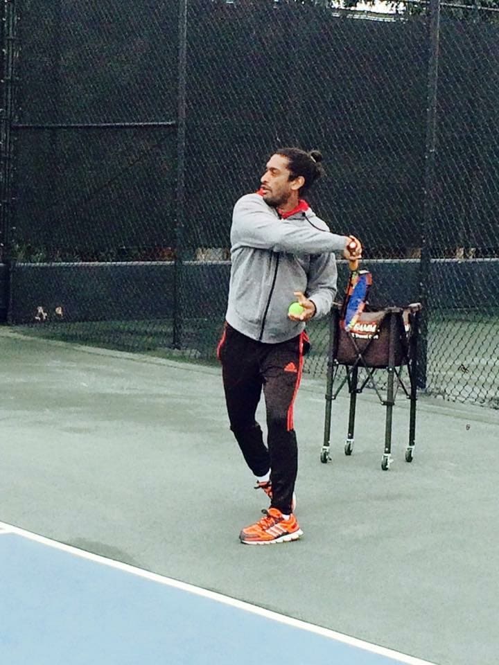 Coach on a court with a ball cart, hitting a forehand