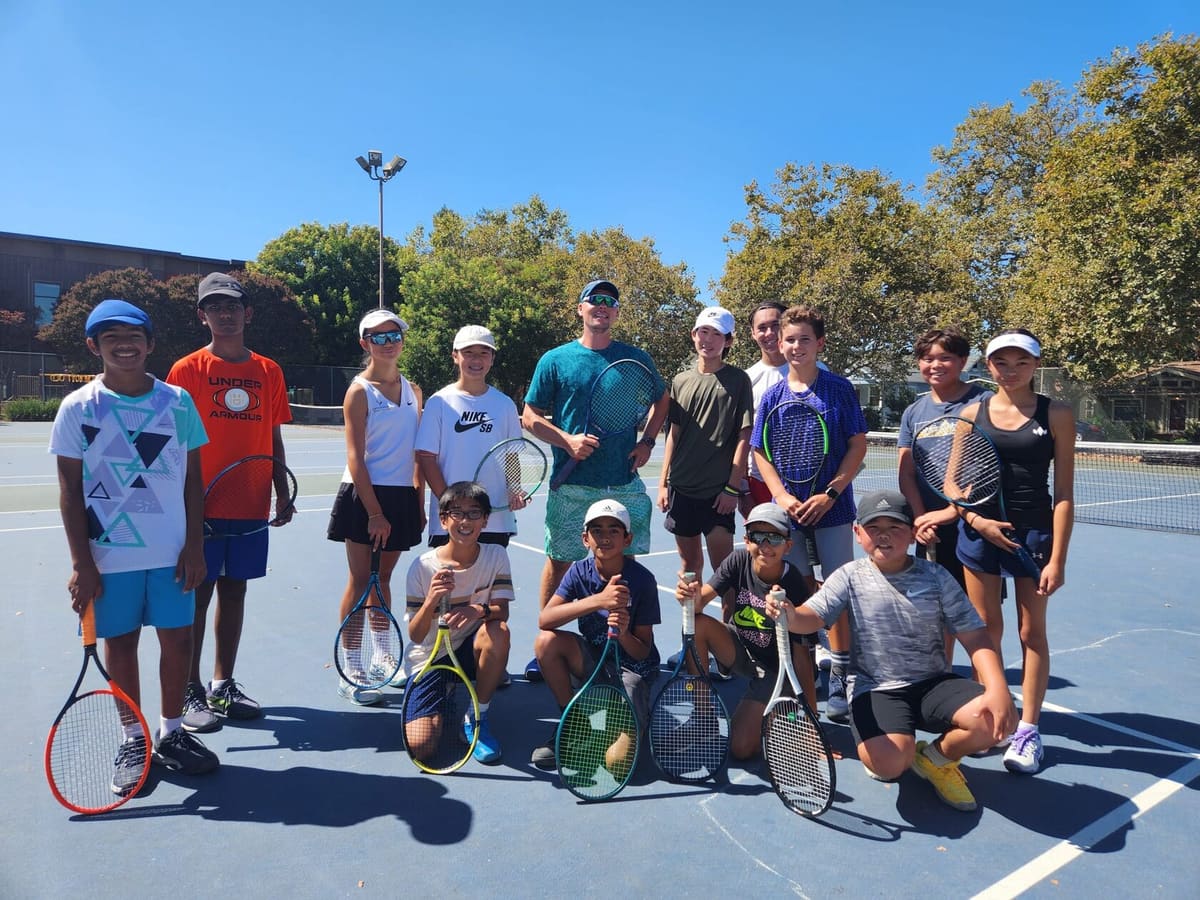 Group of young players and coaches posing on a court