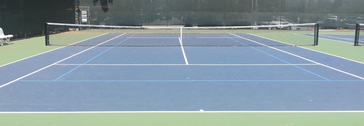 Blue tennis court with a net on a sunny day